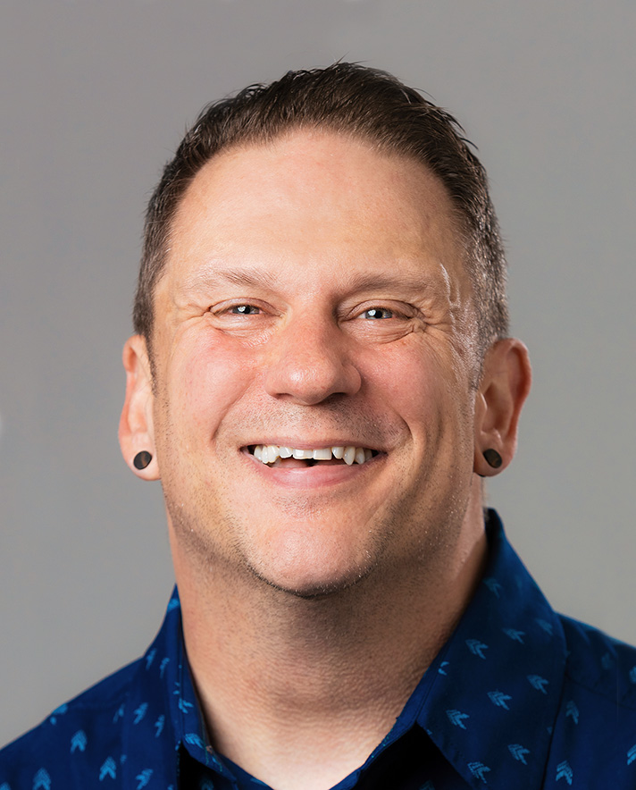 man smiling in blue shirt with grey background
