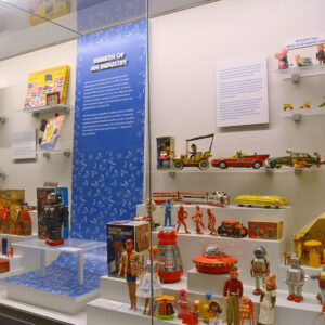 Toys Inc. exhibition featuring a case lined with historical toys and two blue labels.