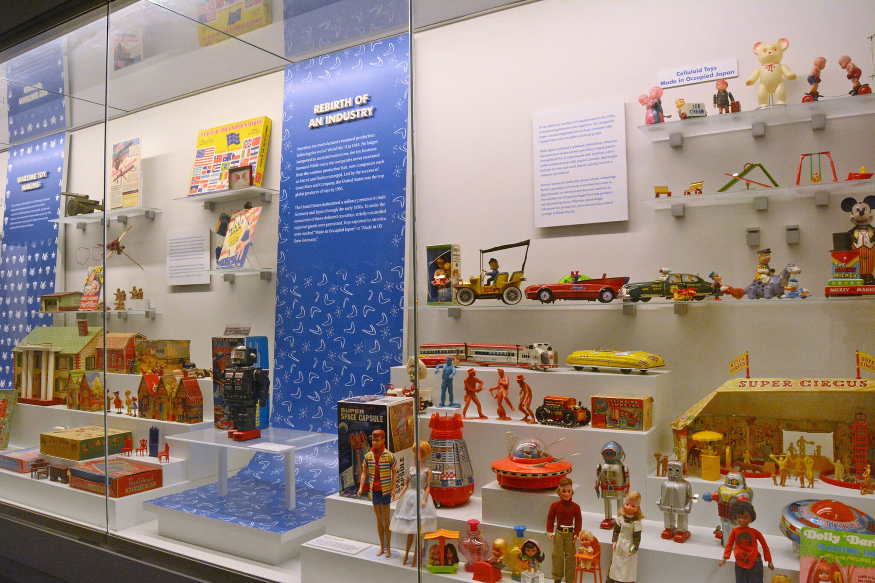 Toys Inc. exhibition featuring a case lined with historical toys and two blue labels.
