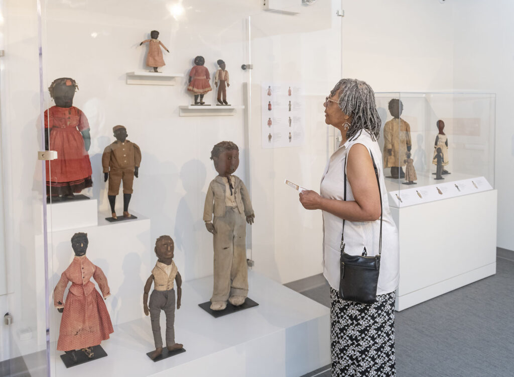 Woman looking at historical Black Dolls displayed in a case.