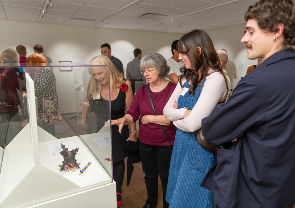 a diverse group of people view an item in a glass case