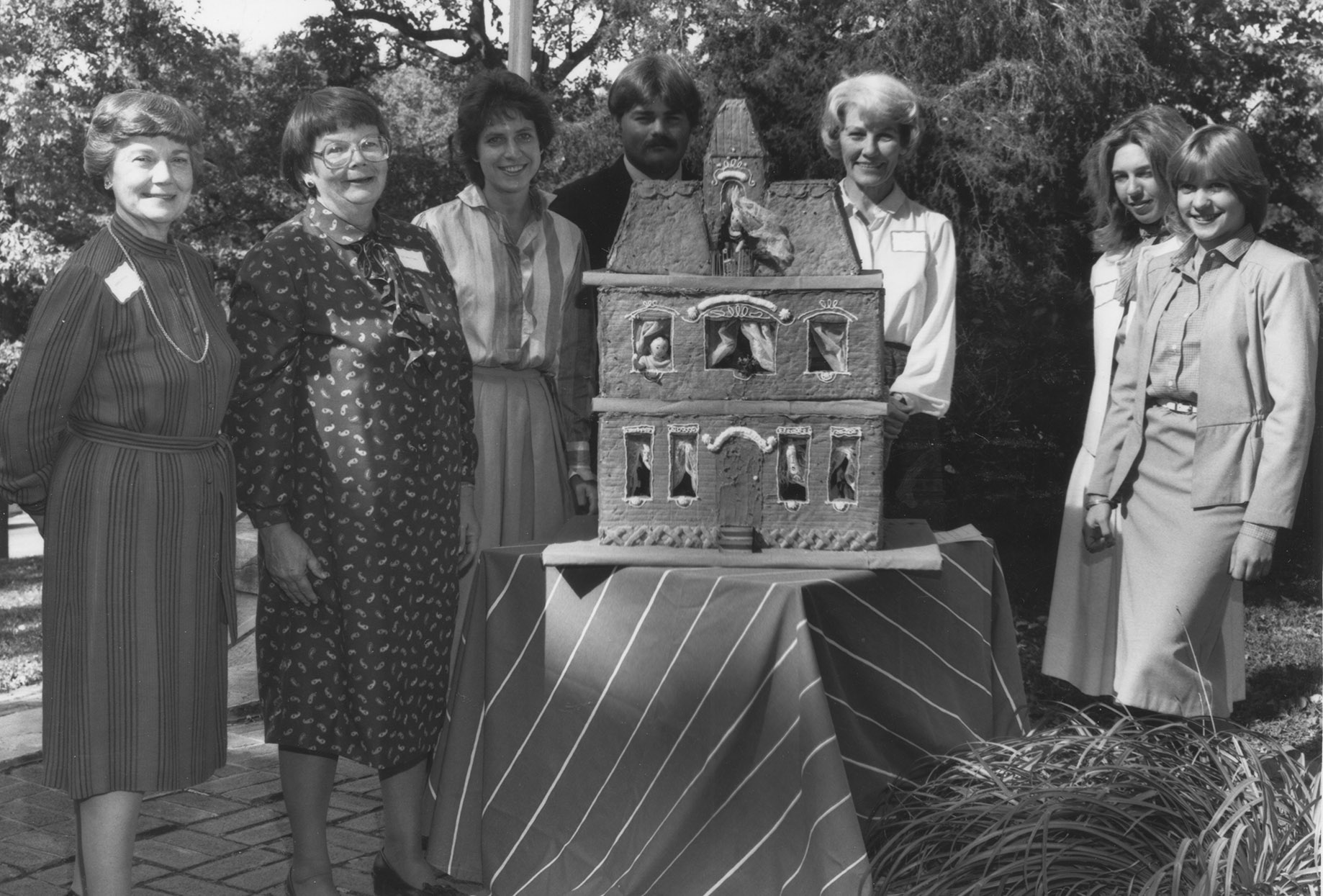 Historical photo of Museum founders with a dollhouse themed cake.