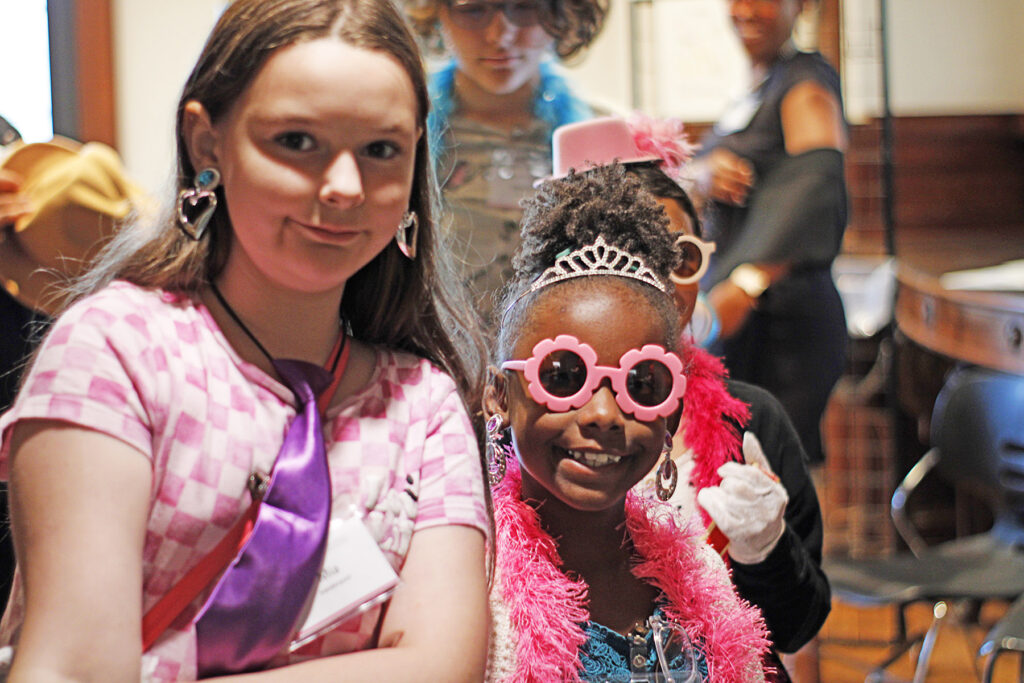 Two girls wearing fun items from a dress-up closet.