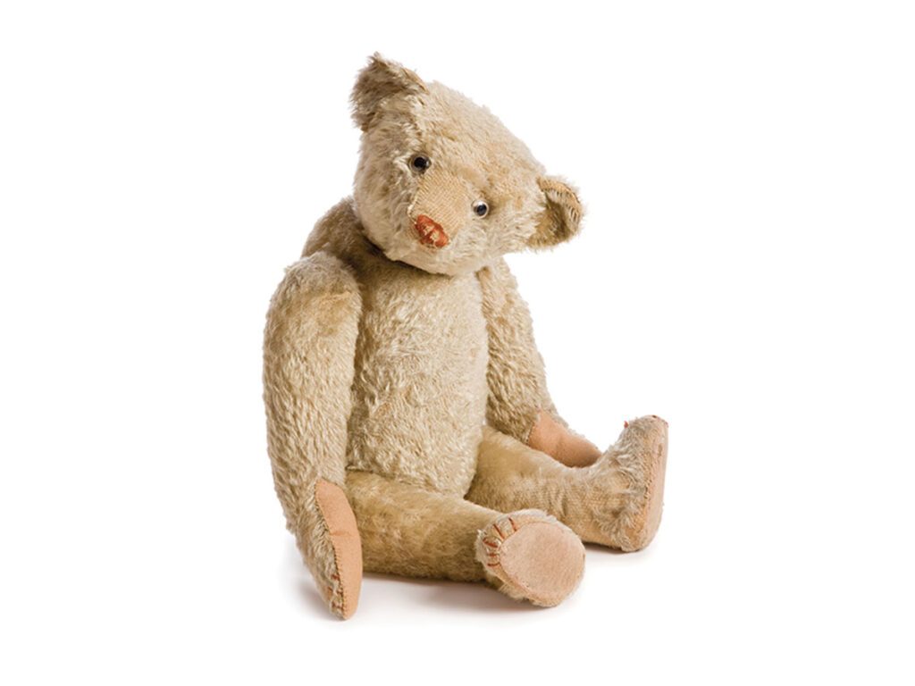 Tan colored teddy bear with its head tilted.