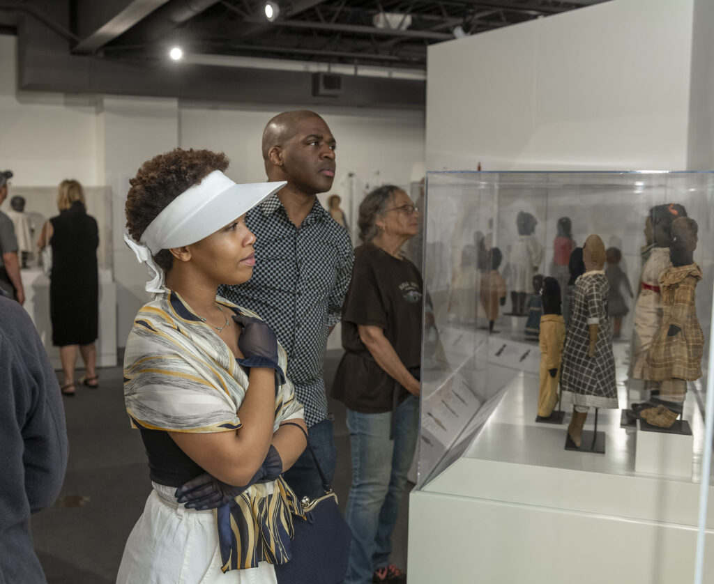 Visitors looking at cases of historical Black dolls.