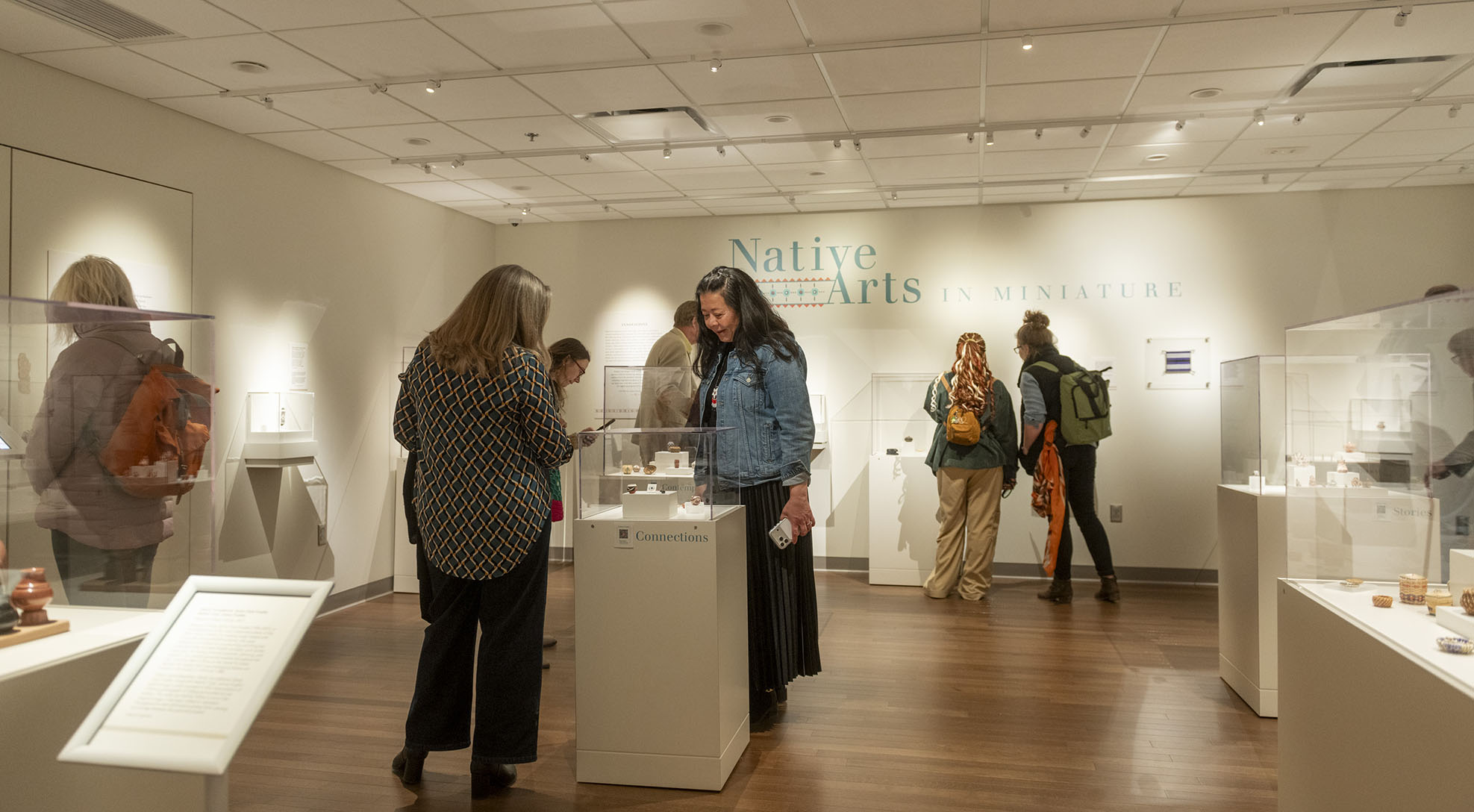 Visitors looking at miniature Native American art.