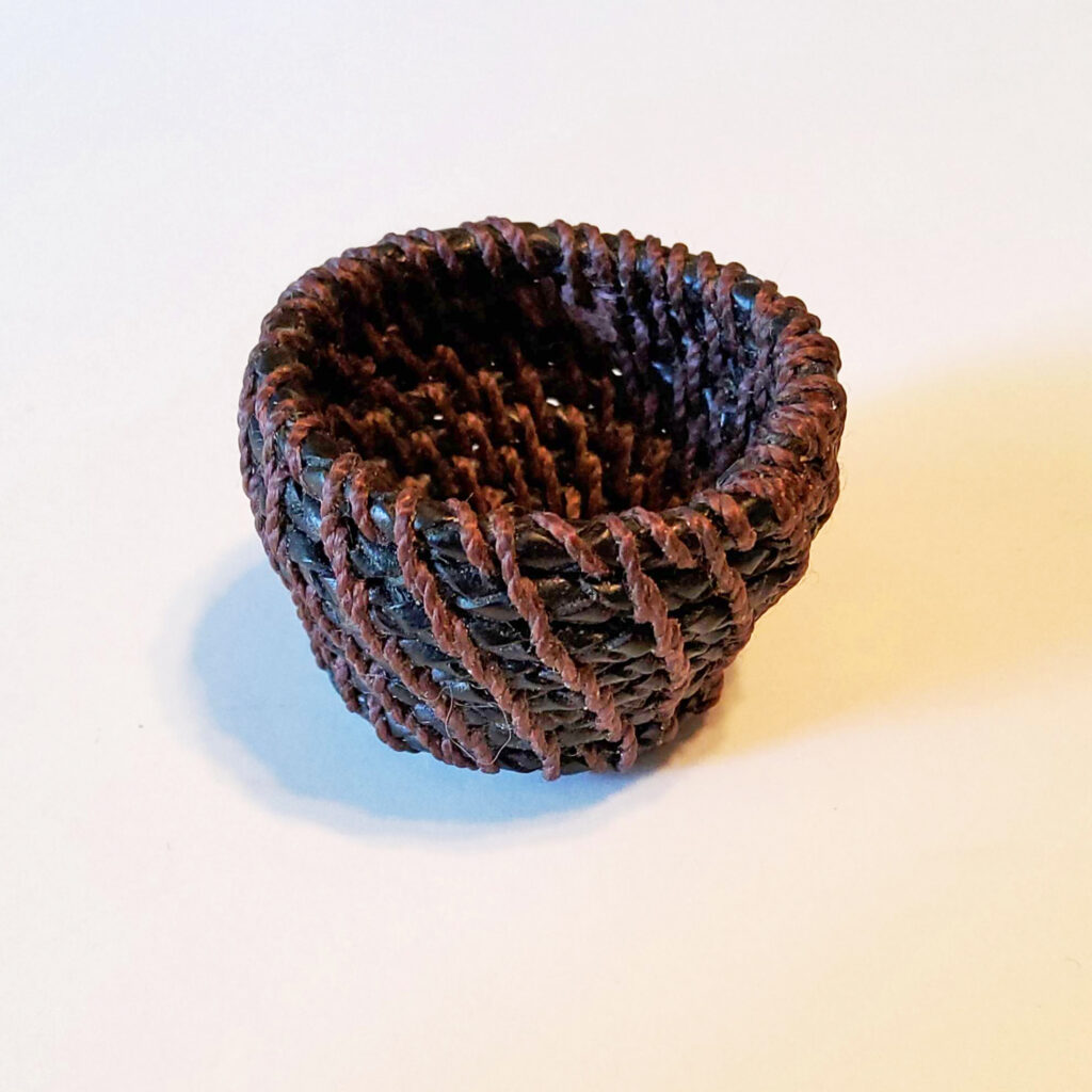 Miniature woven basket made of brown materials.
